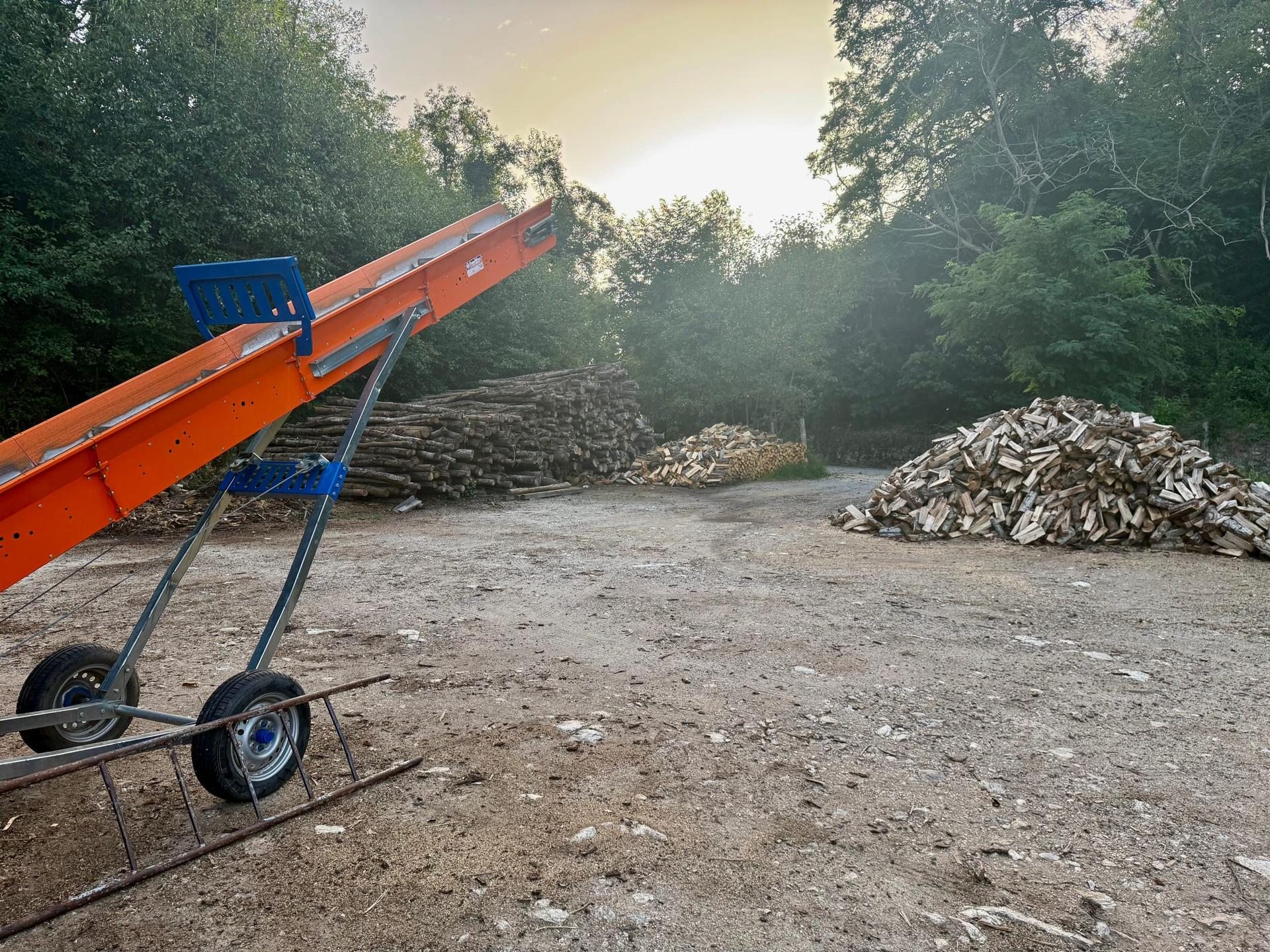 Impianto di spaccatura e cataste di legna da ardere al tramonto
